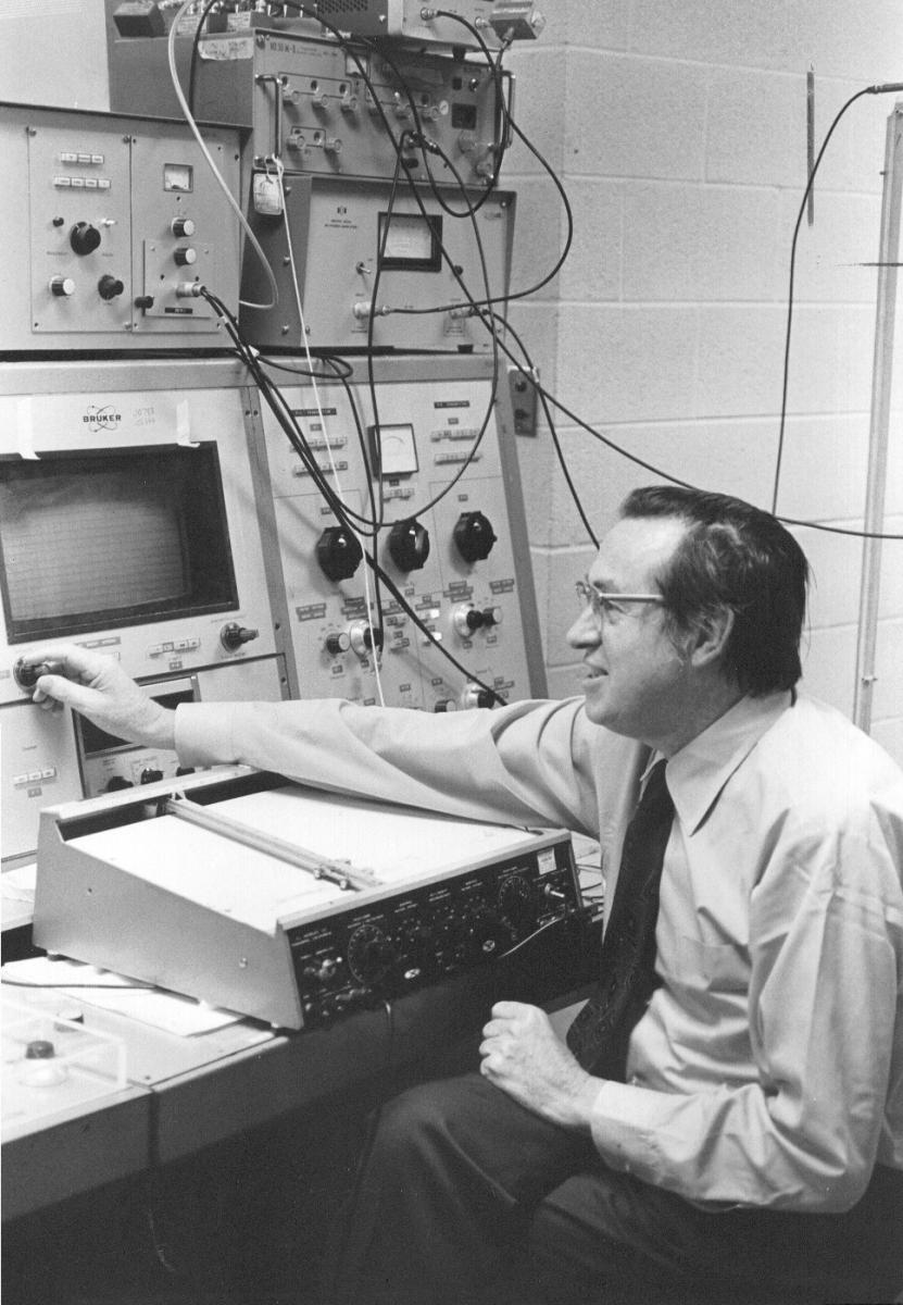 an old image of Max T. Rogers in front of a NMR Spectrometer